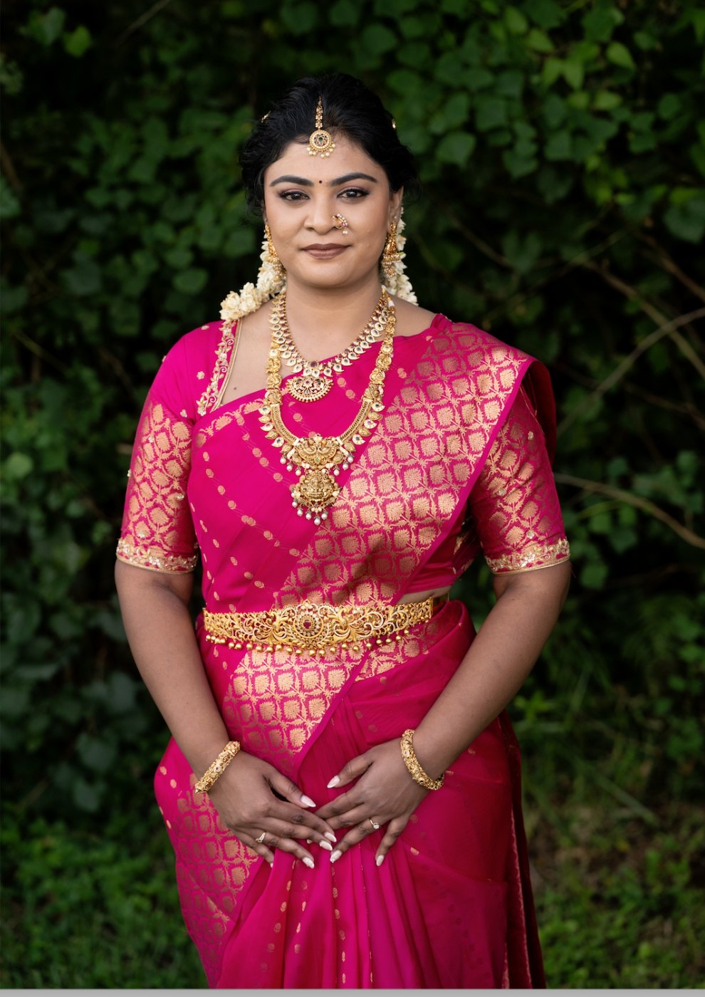 Indian bride in a pink silk saree with bridal makeup, hair and jewellery by Varavi in Tampa